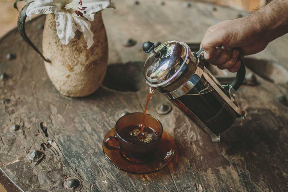 Café french press sendo servido em xícara de vidro