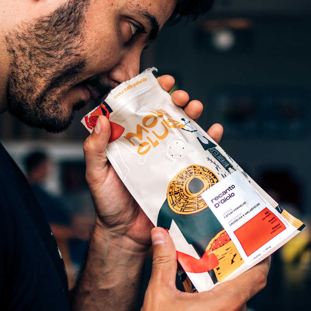 Homem cheirando pacote de cafe