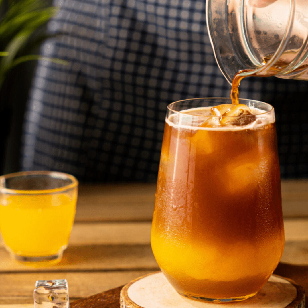 Café gelado com limão sendo servido em copo de vidro