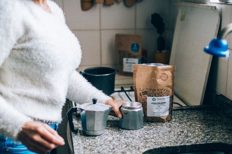 mulher preparando cafeteira italiana na cozinha