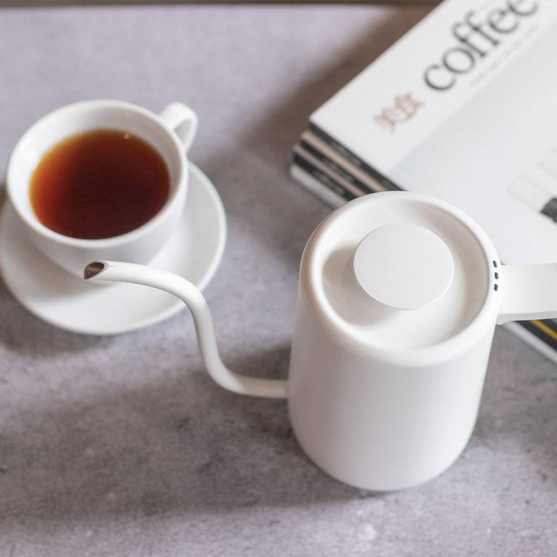 Chaleira branca Timemore, xícara branca com café e livros