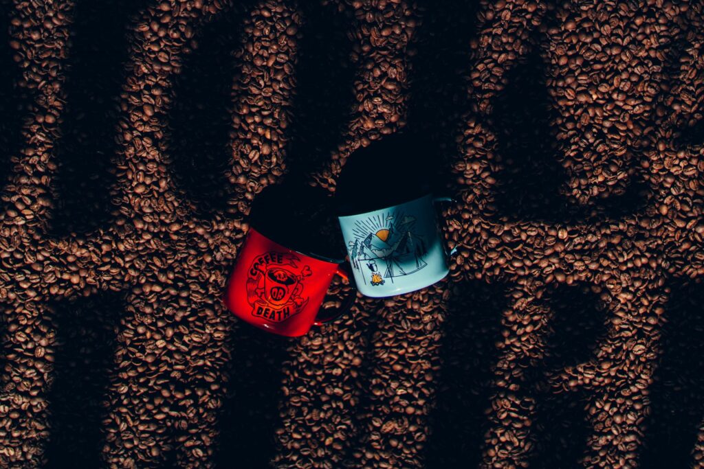Canecas colocadas sobre grãos de café com a escrita Moka Clube sobre eles em uma espécie de sombra