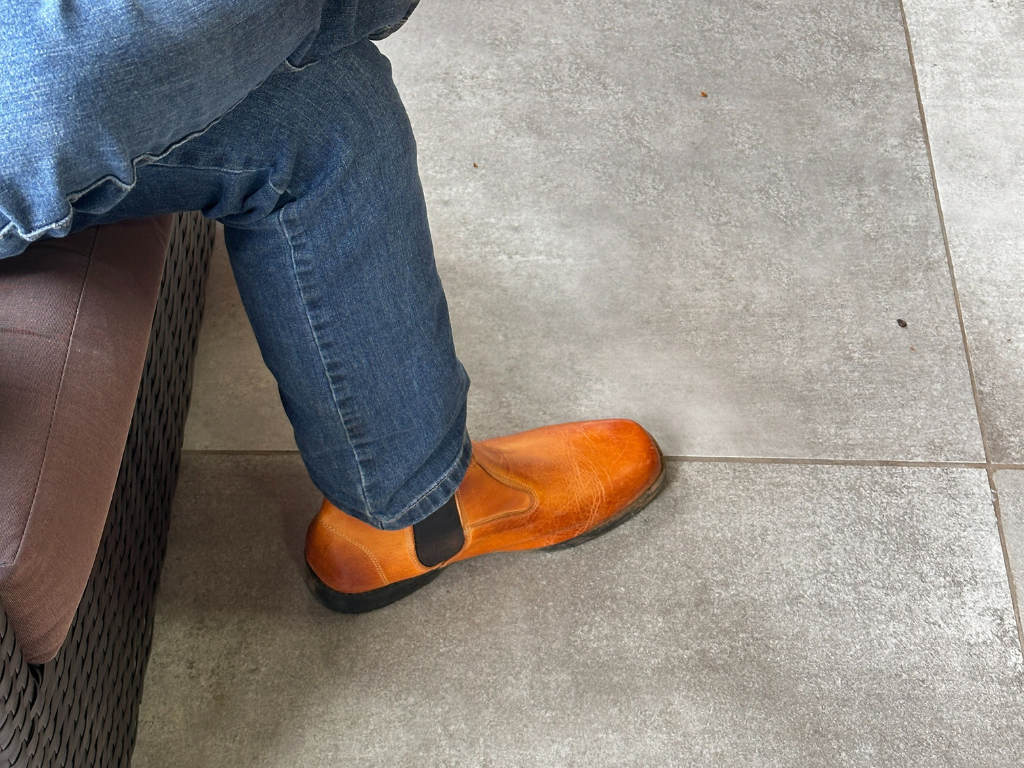 Pernas de homem de calça jeans e bota sentado