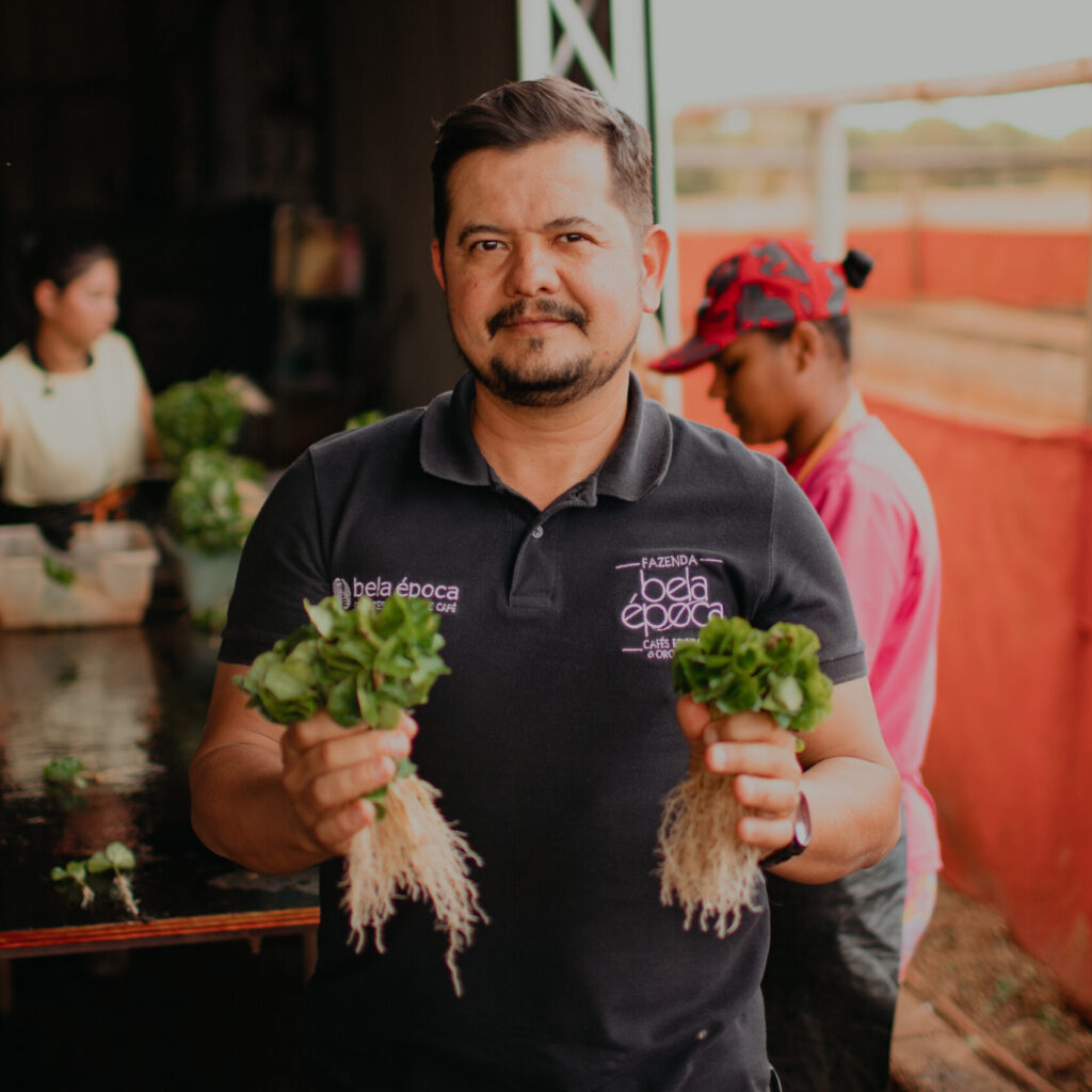 Homem segurando mudas de plantas e mulheres atras