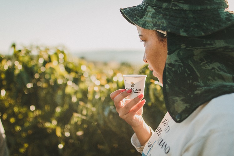 Mulher tomando café olhando para plantação